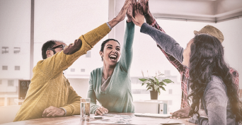 A cheerful business team giving each other a high-five while sitting in a creative office, celebrating success.